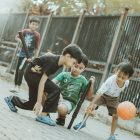 Children play together with a ball and sticks.