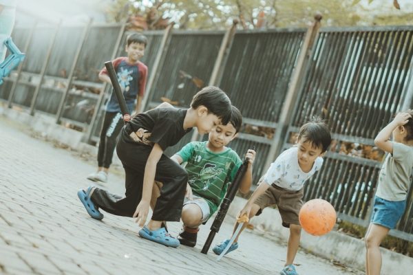 Children play together with a ball and sticks.
