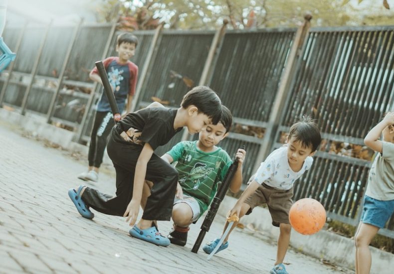 Children play together with a ball and sticks.